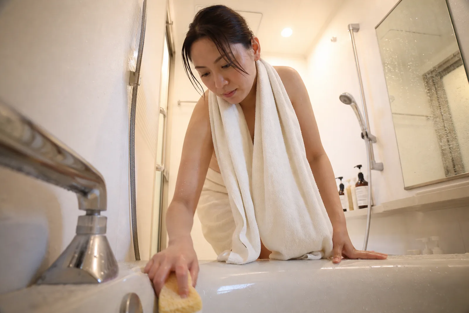 浴室バスタブの給湯口からの一人称視点。広角レンズによる構図で、カランが自然に映り
