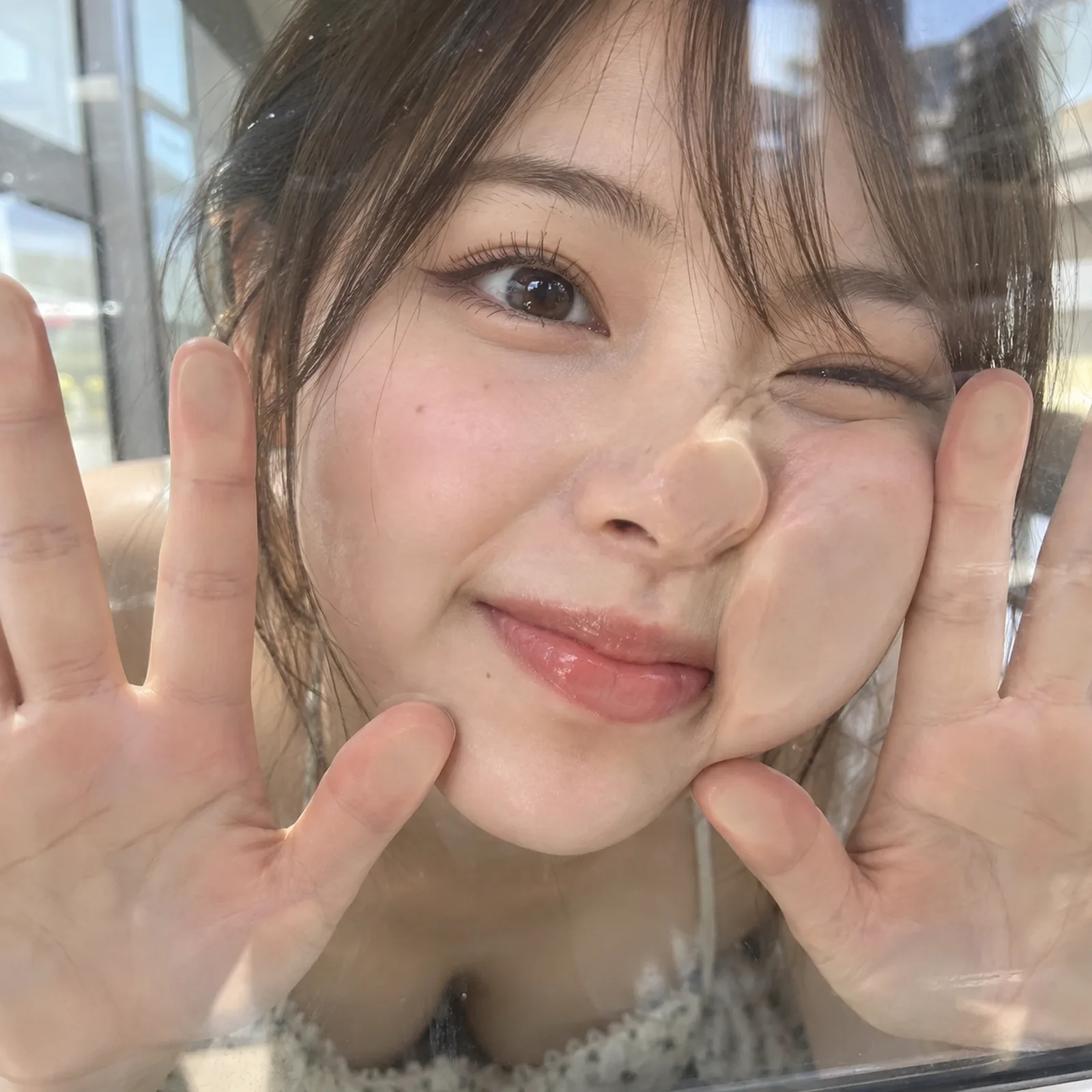 女性は窓ガラスの向こう側から片頬と両手のひらをガラス面にぴったり押しつけて笑って